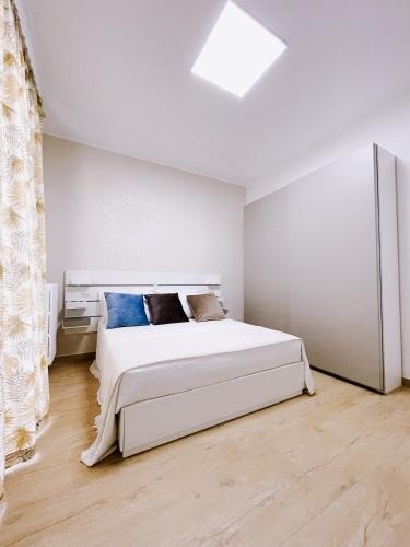 a white bedroom with a large white bed with blue pillows at REGINA ANNA HOME in Bari