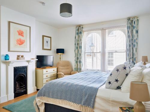 a bedroom with a bed and a tv and a fireplace at Finest Retreats - Centre View in Sidmouth