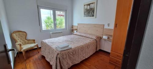 a bedroom with a bed and a chair and a window at APARTAMENTO SUJARRERA in Villacarriedo