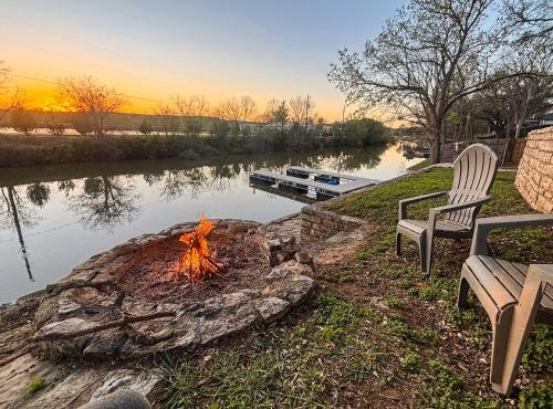 a fire pit next to a river with a bench at Lake Granbury House, Sleeps 11 with Lake Access! in Granbury