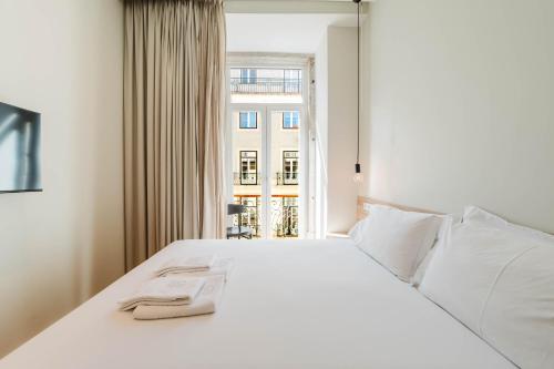 a white bed in a room with a window at GS Chiado Boutique Studios & Suites in Lisbon