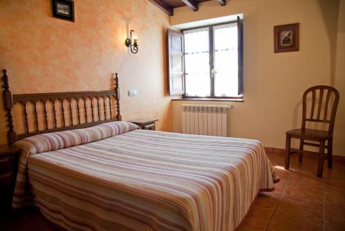 奧瑞那Apartamentos la Roblera的一间带床、窗户和椅子的卧室