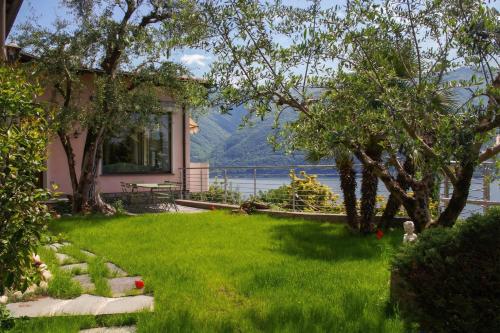 a house with a lawn with a view of the water at Il Tentione in Valsolda