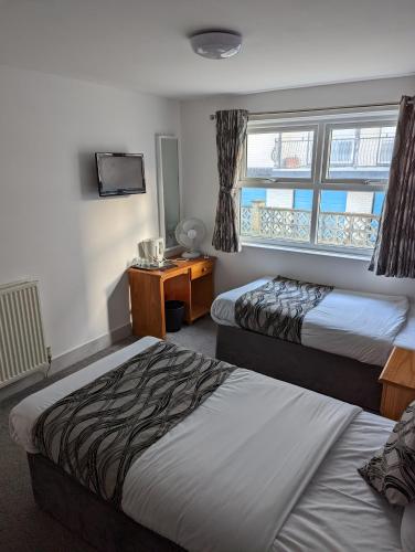 a hotel room with two beds and a desk at Mayfair Hotel -Isle of Wight in Shanklin