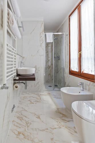 a white bathroom with a sink and a shower at Locanda Correr in Venice