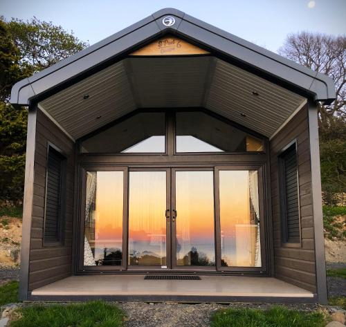 a large window in a shed with a view of the sunset at POD4 Family Glamping with seaview & Wi-Fi in Llwyngwril
