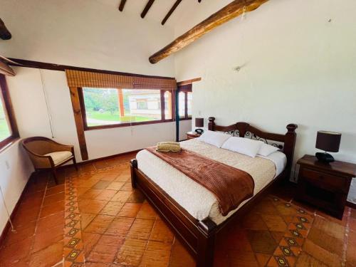 a bedroom with a bed and a chair in it at Hacienda Campestre Oasis de la Villa in Villa de Leyva