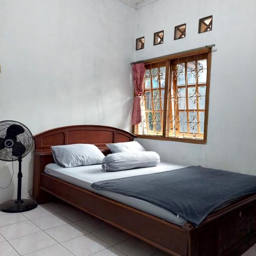 a bed in a bedroom with a window and a fan at Villa Ananda 1, 3 KT Kolam Renang, Karaoke Biliar in Cisarua