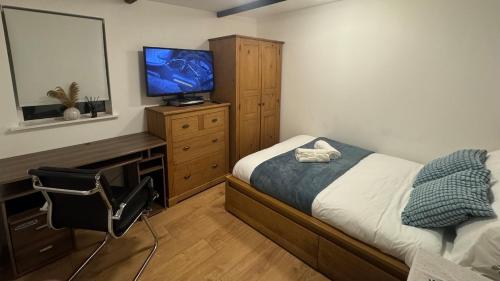 a bedroom with a bed and a television on a dresser at Hidden Gem in Foots Cray