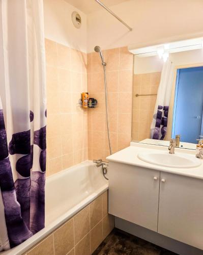 a bathroom with a sink and a toilet and a tub and a mirror at Chez Jiri - Piscine, Balcon vue Alpes, Spacieux T2 in Gex