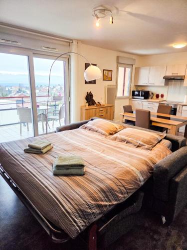 a bedroom with a large bed with two towels on it at Chez Jiri - Piscine, Balcon vue Alpes, Spacieux T2 in Gex