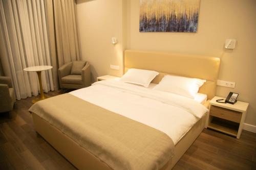 a bedroom with a large bed and a chair at Aristocrat Hotel in Kapchagay