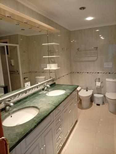 a bathroom with two sinks and a toilet at Hotel Iberflat Marynton in Benicarló