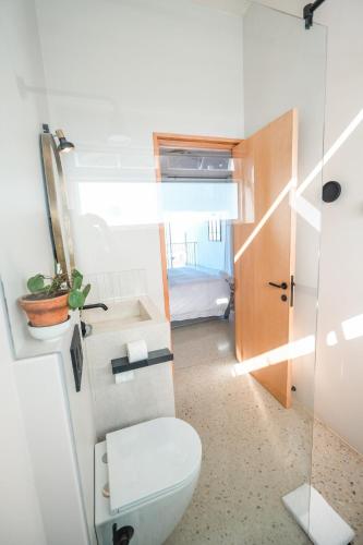 a small bathroom with a toilet and a bedroom at Whale Coast Luxury Suites in Hermanus