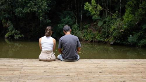 a man and woman sitting on a dock looking at the water at Pousada Refúgio Arauca in Campo Alegre