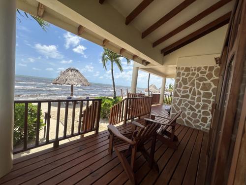 a deck with two chairs and an umbrella and the ocean at Hopkins Bay Belize a Muy'Ono Resort in Hopkins