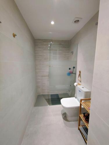 a white bathroom with a toilet and a shower at Apartamento luminoso a 100mts playa, ambiente tranquilo in L'Escala