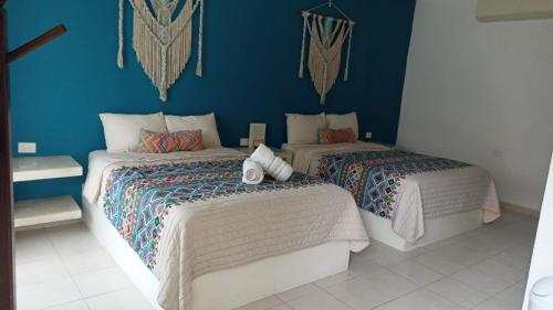 two beds in a room with blue walls at Azul 36 Hotel in Bacalar