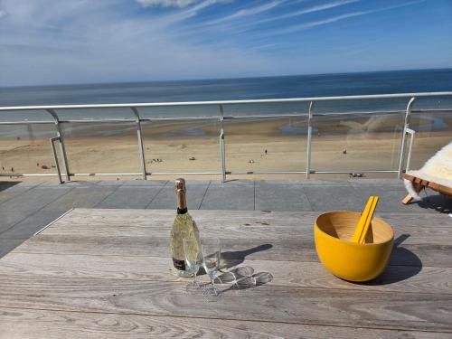 a bottle and glasses sitting on a table near the beach at Secret Stay, Wellness Penthouse studio, Privacy, Seaview, Terras, Sauna in Koksijde