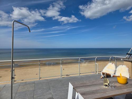 a table on a balcony with a view of the beach at Secret Stay, Wellness Penthouse studio, Privacy, Seaview, Terras, Sauna in Koksijde