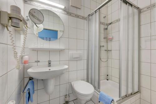 a bathroom with a toilet and a sink and a shower at Hotel zum Kater in Rostock