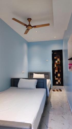 a bedroom with two beds and a ceiling fan at Amirtham Holiday Home in Kovakulam