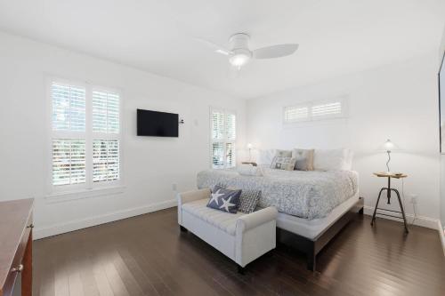 a white bedroom with a bed and a chair at Weeden Cottage in St. Augustine