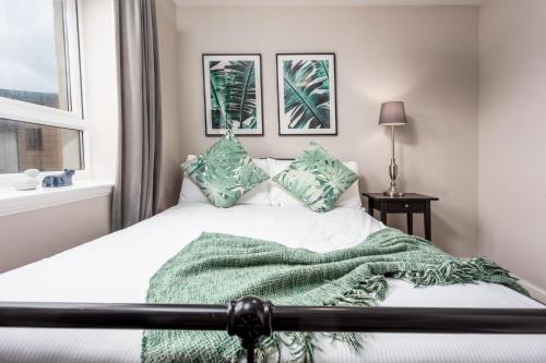 a bedroom with a bed with a green blanket at Bay View - Donnini Apartments in Ayr