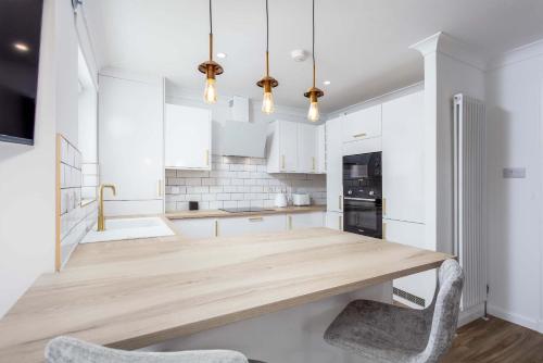 a kitchen with a wooden table and two chairs at Harbour House - Donnini Apartments in Ayr