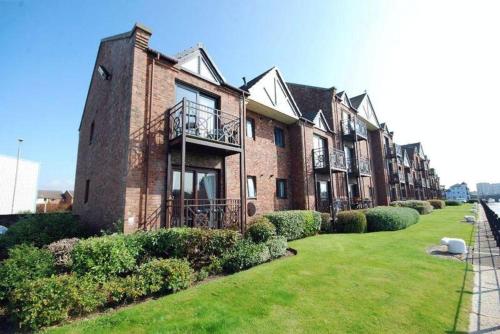 a large brick building with a lawn in front of it at Harbour House - Donnini Apartments in Ayr