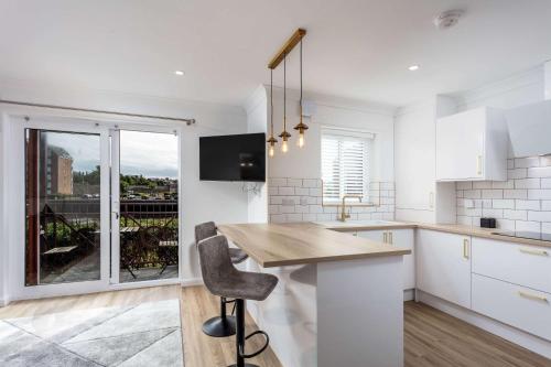 a kitchen with white cabinets and a table with a chair at Harbour House - Donnini Apartments in Ayr