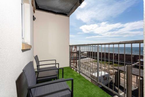 a balcony with two chairs and a view of the ocean at Carrick Retreat - Donnini Apartments in Ayr