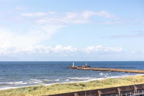a pier stretches out into the ocean with a lighthouse at Carrick Retreat - Donnini Apartments in Ayr