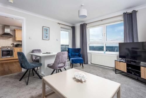 a living room with a tv and a table and chairs at Carrick Retreat - Donnini Apartments in Ayr