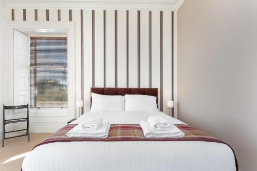 a bedroom with a large bed with towels on it at Sea Breeze - Donnini Apartments in Ayr