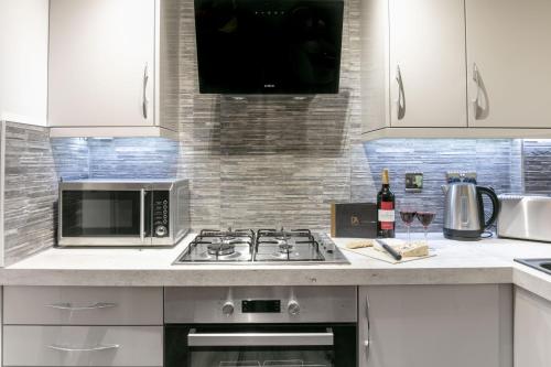 a kitchen with a stove and a microwave at Forbes Retreat - Donnini Apartments in Ayr