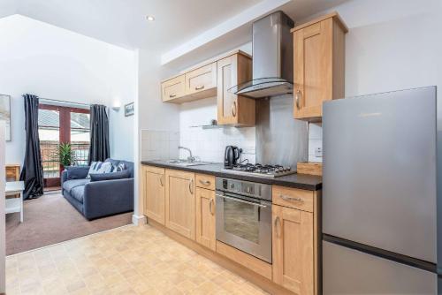a kitchen with wooden cabinets and a stainless steel refrigerator at Elliot Suite No 1 - Donnini Apartments in Ayr