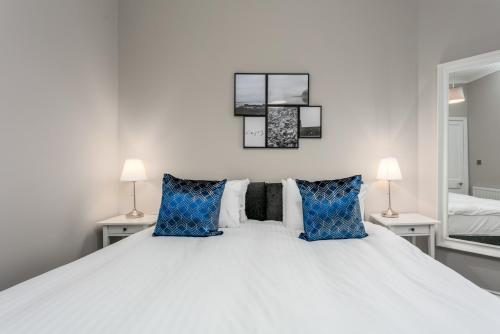 a bedroom with a large white bed with blue pillows at Seaforth Suite - Donnini Apartments in Ayr