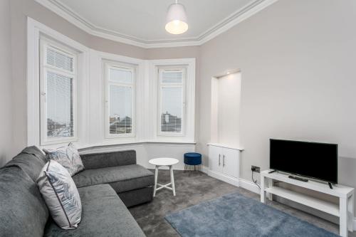 a living room with a couch and a flat screen tv at Seaforth Suite - Donnini Apartments in Ayr