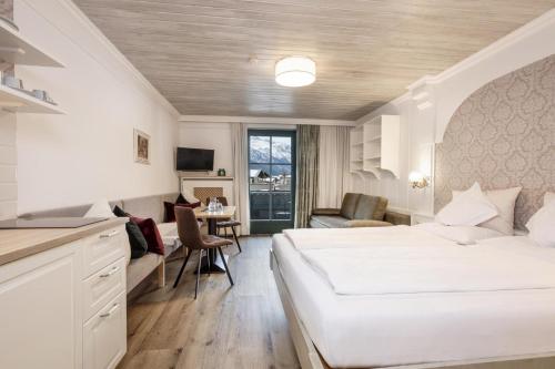 a bedroom with a large white bed and a desk at Hotel Garni Keil in Kleinarl