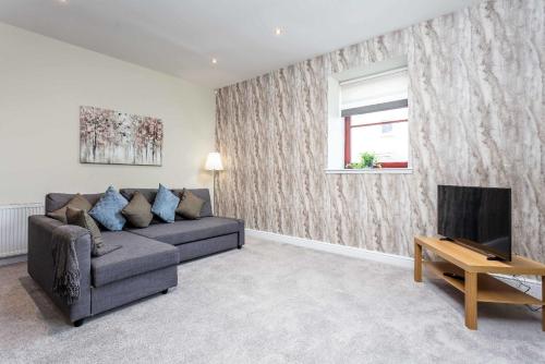 a living room with a couch and a television at Granary Suite No3 - Donnini Apartments in Ayr
