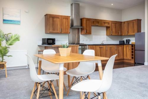 a kitchen with a wooden table and white chairs at Granary Suite No3 - Donnini Apartments in Ayr