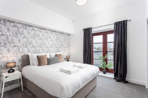 a bedroom with a large white bed and a window at Granary Suite No3 - Donnini Apartments in Ayr