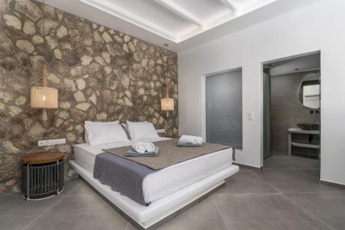 a bedroom with a large bed and a stone wall at Villa Leuki in Adamantas