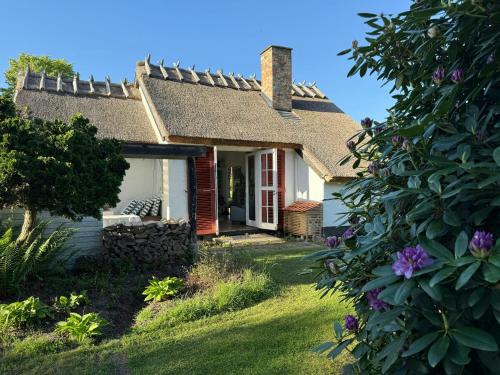 a small white house with a grass yard at Thatched Cottage Near Dronningmølle Beach in Dronningmølle