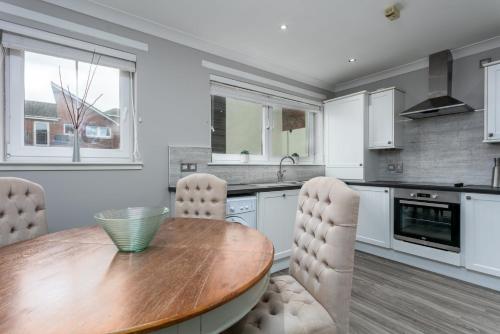 a kitchen with a wooden table and white cabinets at Iona Residence - Donnini Apartments in Ayr