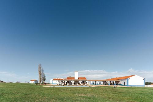 a building with a grassy field in front of it at Charming Farm House With Pool in Ferreira do Alentejo