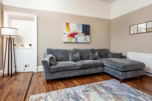 a living room with a gray couch and a rug at Main Street View - Donnini Apartments in Prestwick