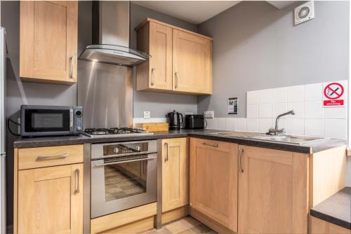 a kitchen with wooden cabinets and a stove top oven at Elliot Suite No3 - Donnini Apartments in Ayr