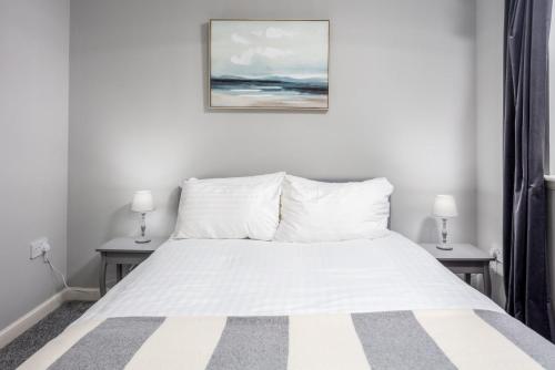 a bedroom with a white bed with two lamps at Millbrae Residence - Donnini Apartments in Ayr